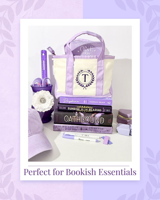 Tote bag with monogram, books, and stationery items on a light purple background