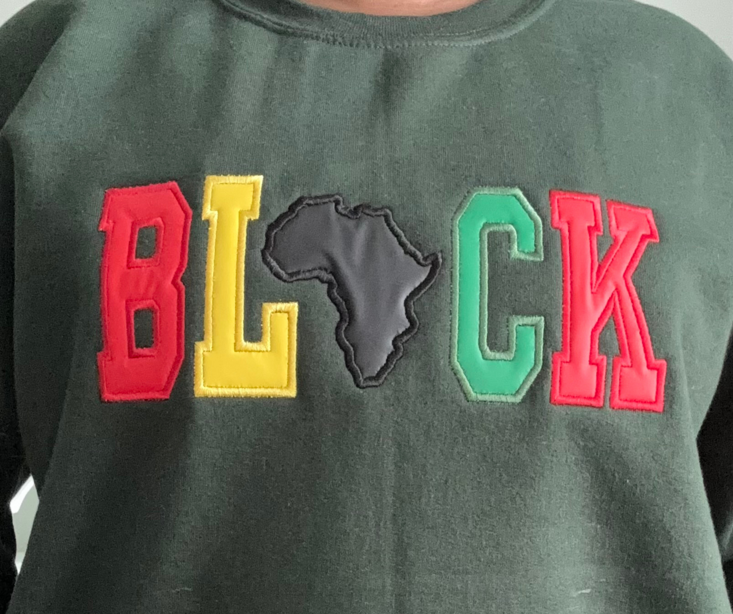 Close-up of BLACK appliqué embroidery with Africa silhouette detail and textured stitching
