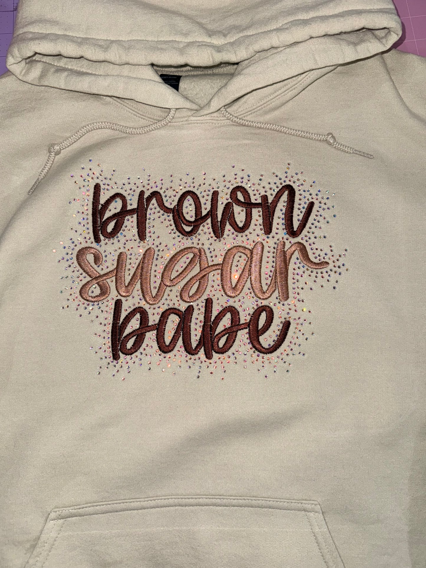Tan-colored hoodie with decorative text design brown sugar babe with rhinestone detailing