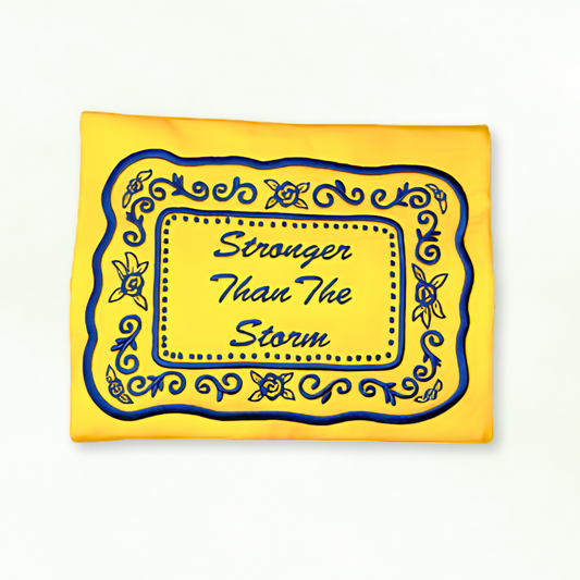 Yellow sweatshirt with blue decorative border and text 'Stronger Than The Storm' on a white background