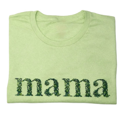 Folded green t-shirt with floral embroidery 'mama' text on a white background