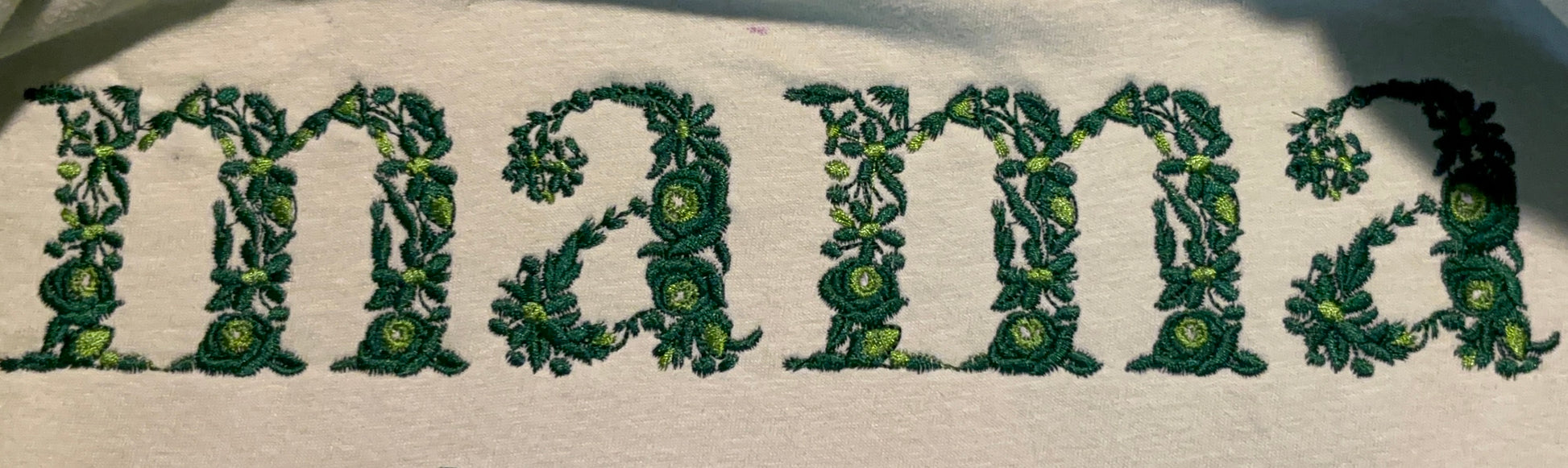 Embroidered 'mama' with decorative green floral patterns