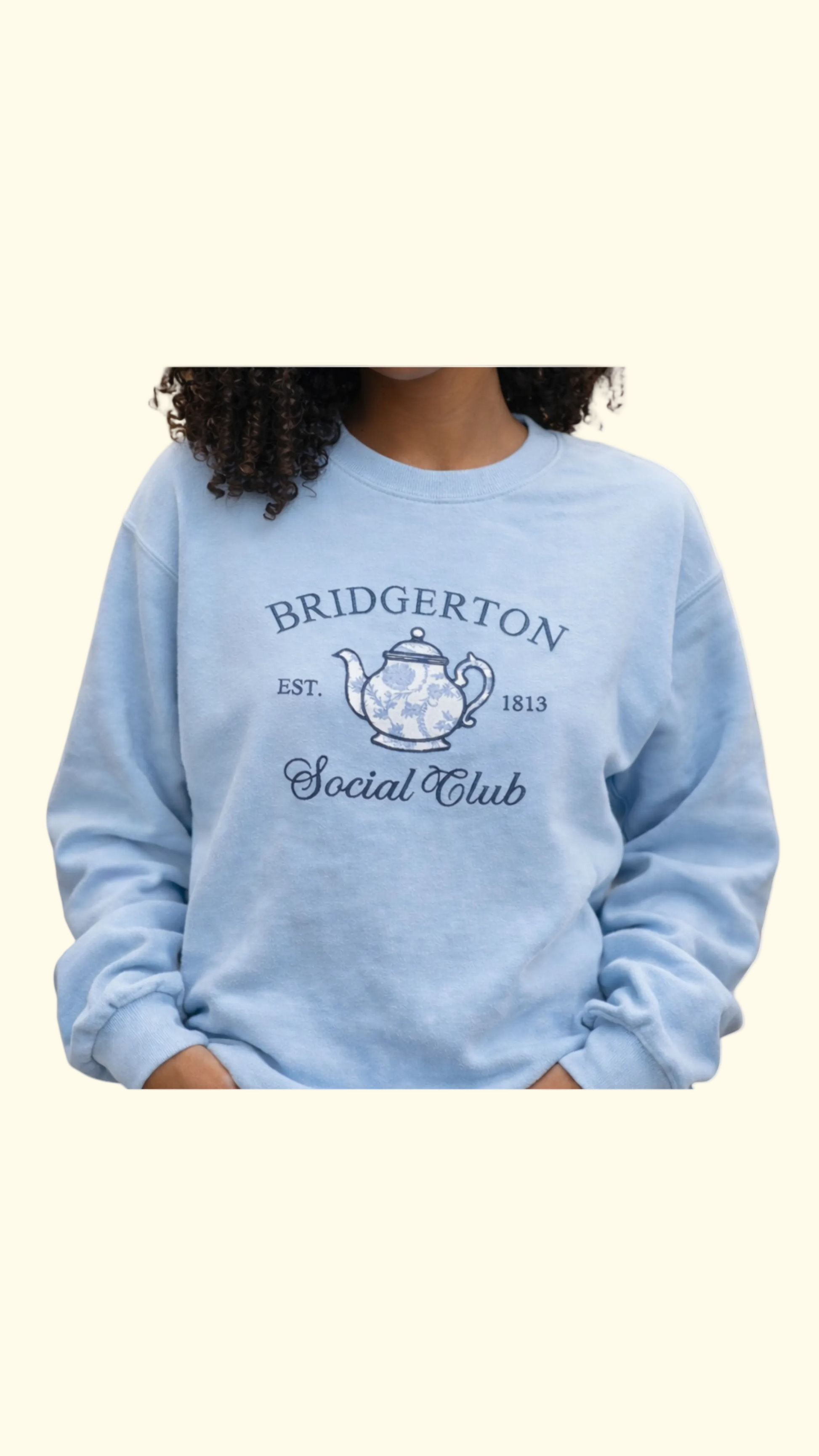 African American woman wearing Tea Time regency inspired bookish embroidered sweatshirt in bookstore, cozy romance reader outfit