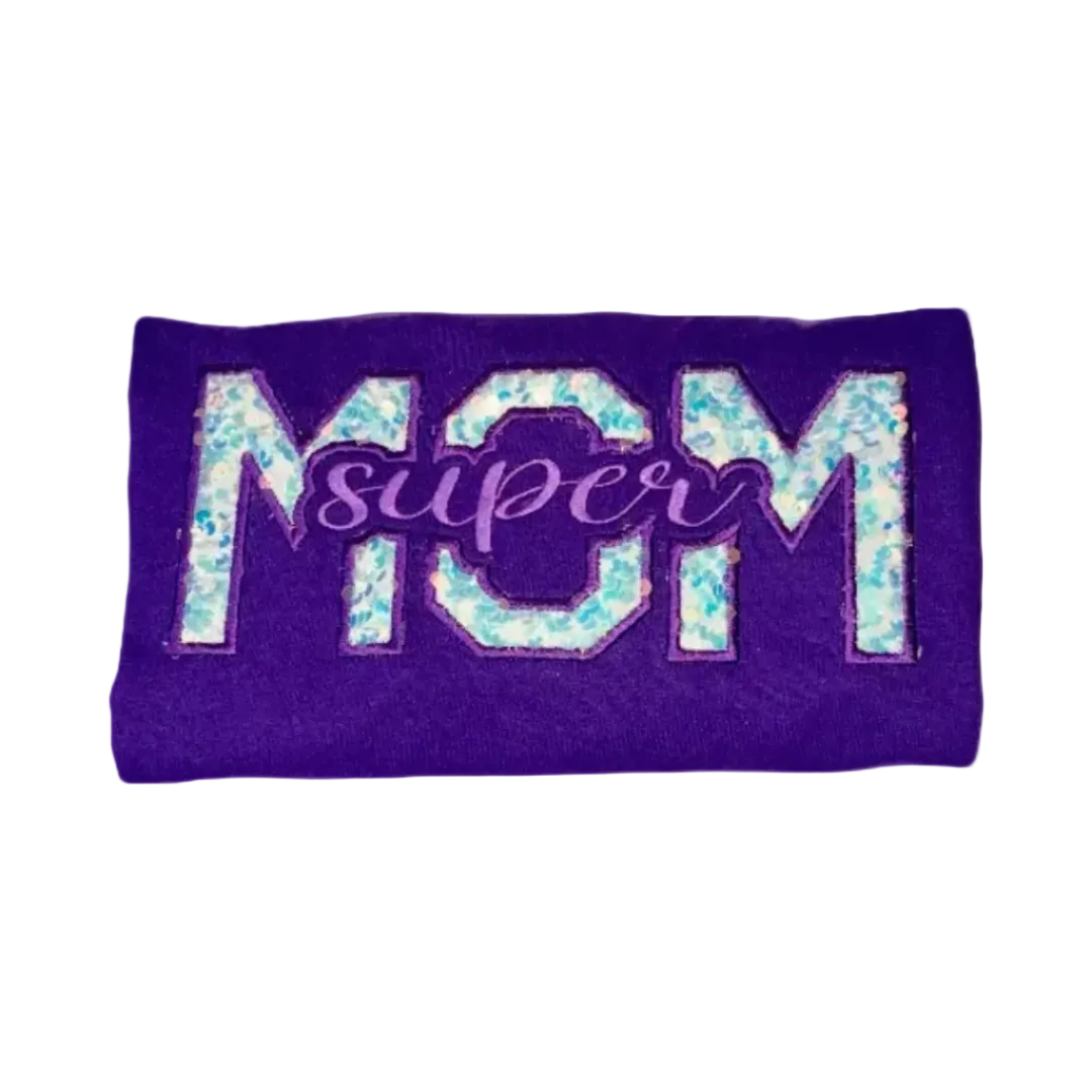 Purple folded T-shirt with a sparkly sequin and embroidered Super Mom design in varsity-style lettering.