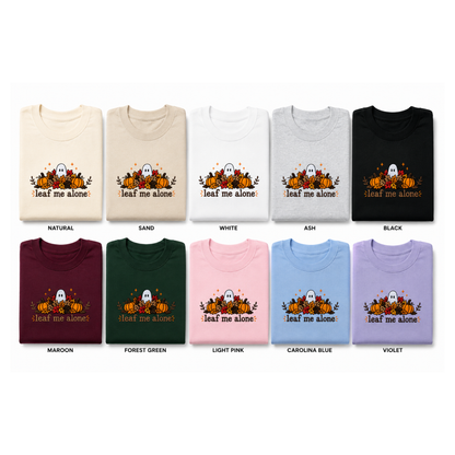 A grid of folded T-shirts showing the same embroidery in multiple color options. The image features pumpkins, ghosts, leaves, and the text 'leaf me alone".