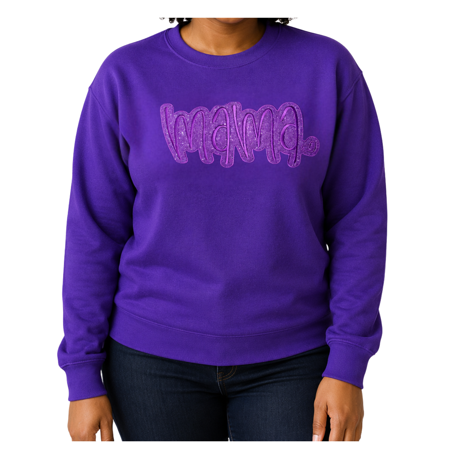 A person wearing a purple crewneck sweatshirt with a glittery 'mama' graphic across the chest, paired with dark blue jeans, shown against a plain white background.