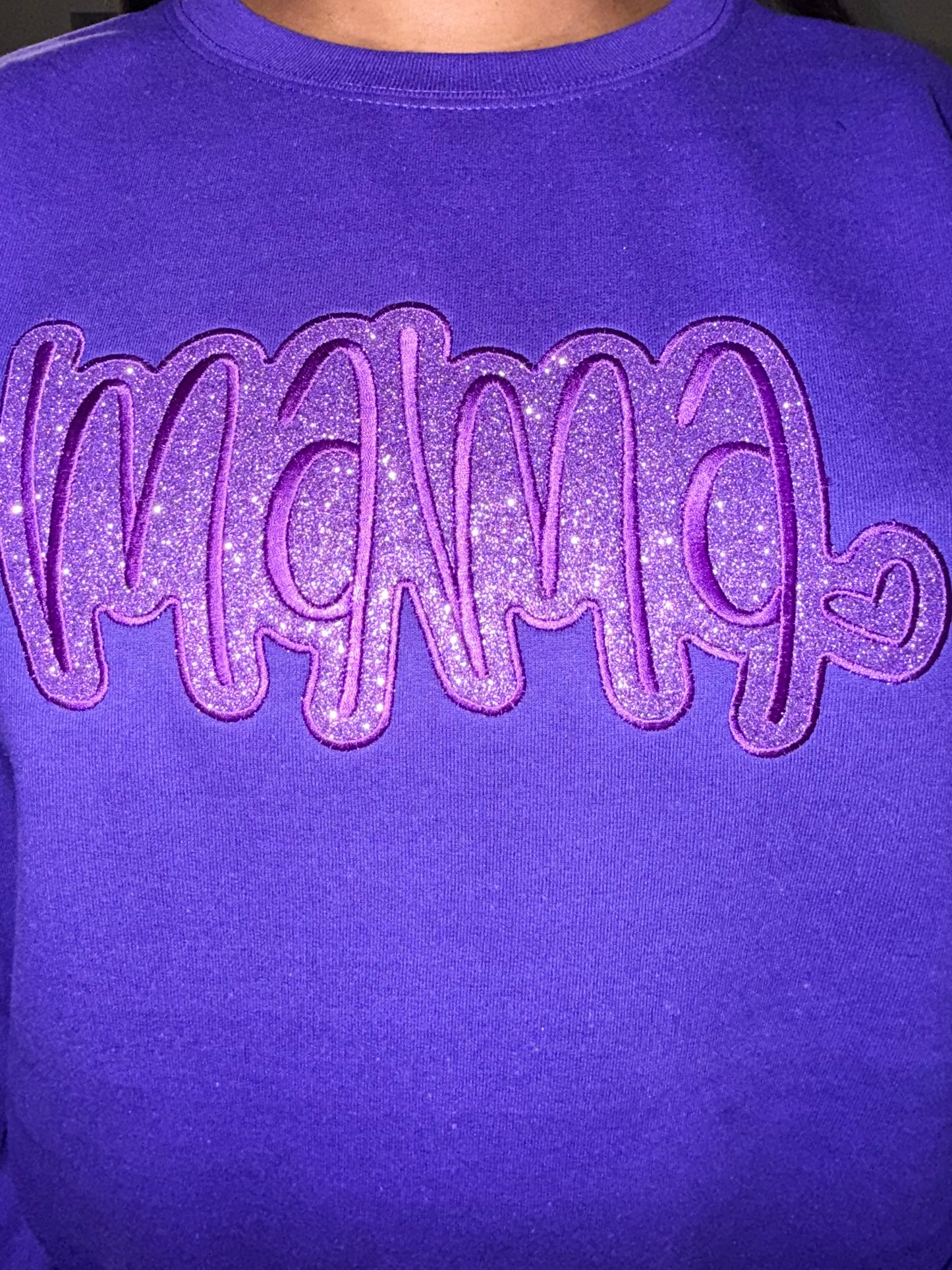 female wearing a Purple sweatshirt with 'MAMA' in glittery embroidery and HTV